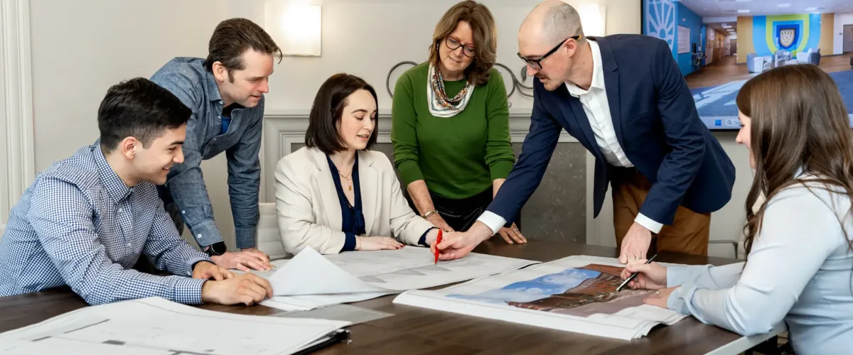 SV Design employees collaborating around drawings on a tabletop