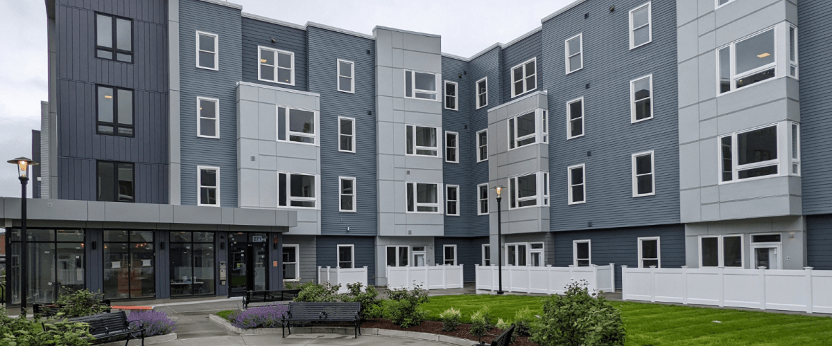 view of 4 story multifamily building facade and landscaping in front