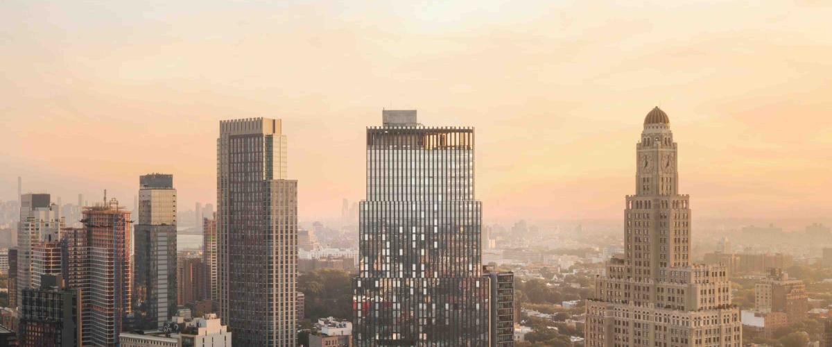 A golden-hour view of the Brooklyn skyline featuring a modern stepped glass skyscraper at its center.