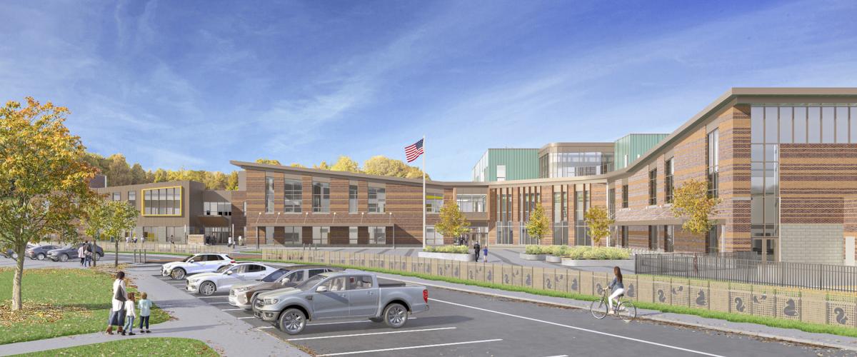 Large brick school building with an adjacent parking lot and open green space under a clear blue sky.