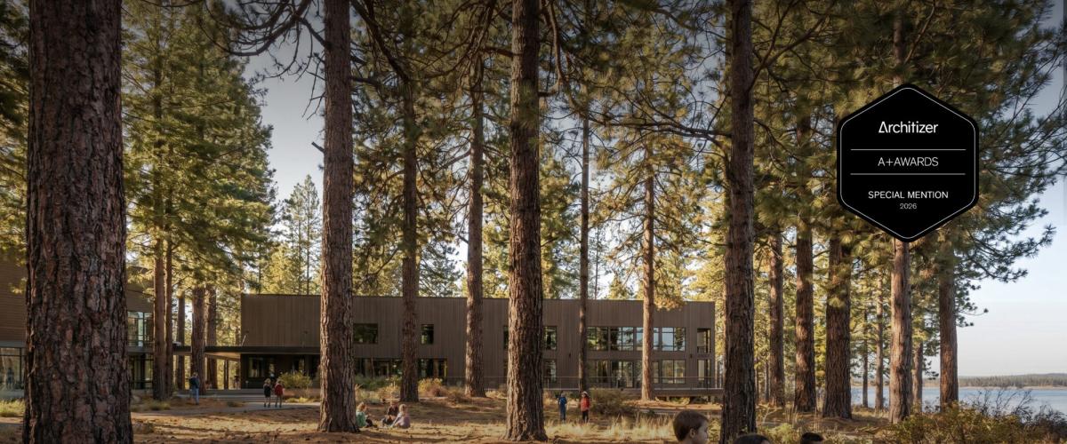 A modern, wooden building nestled among tall pine trees.