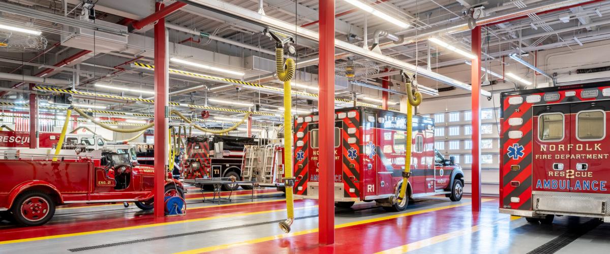 Interior view of the garage holding multiple ambulances and features bright red support columns