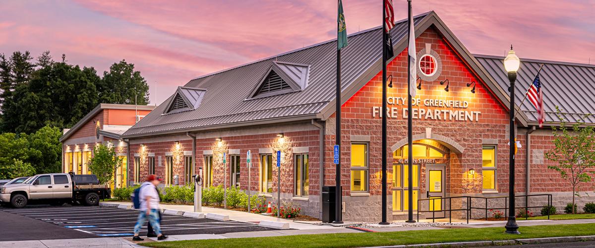 Exterior corner of the building featuring a pitched room and red brick colored stone unit facade