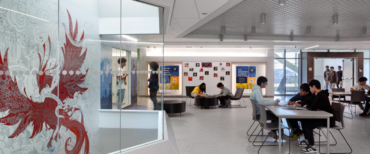 Students collaborating at tables and lounge chairs in the schools project area