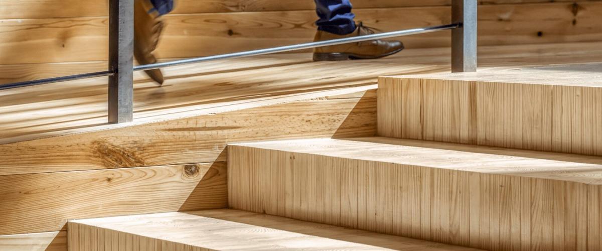 A close-up of modern wooden stair, highlighting the natural wood grain and laminated construction.