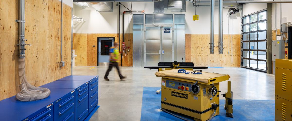 A clean, organized workshop space with plywood-paneled walls and large roll-up doors.