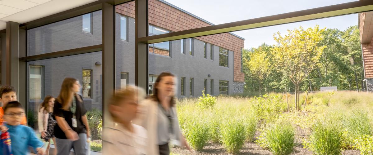 Interior hallway shot showing large and bright windows looking out to green open lawn