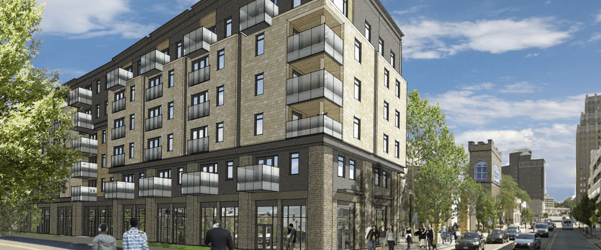 Architectural rendering of The Nest, a six-story affordable multifamily building in Niagara Falls, shown from the street with brick façades, balconies, and ground-floor entrances.
