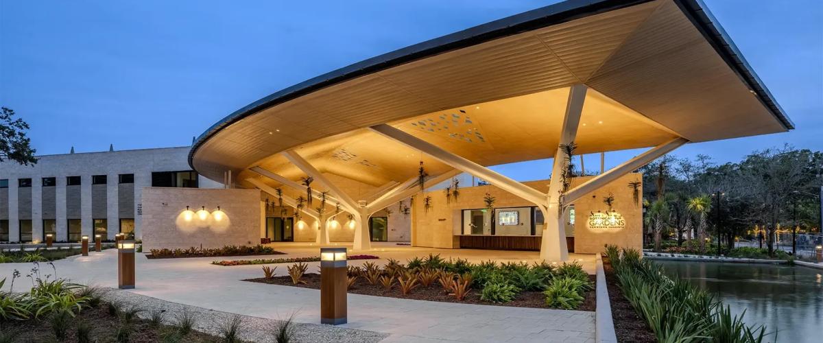 The entrance to Marie Selby Botanical Gardens, showcasing contemporary architecture with a distinctive, sweeping roofline and surrounding landscaping.