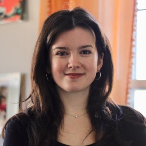 Brunette white woman in front of orange curtained window
