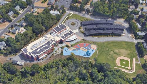 Aerial view of Maria Hastings Elementary School showing rooftop solar arrays and solar canopies above parking area