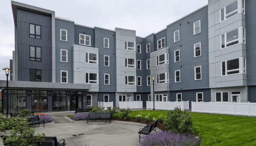 view of 4 story multifamily building facade and landscaping in front