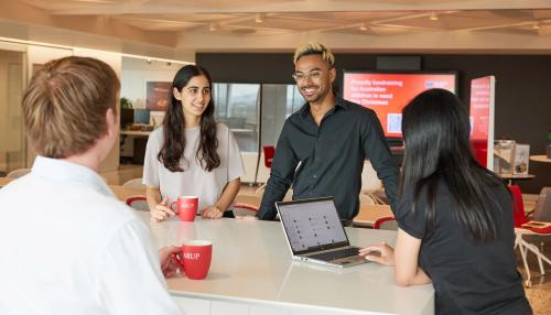Four professionals gathered around a table within an Arup office with Arup branded coffee cups in hand