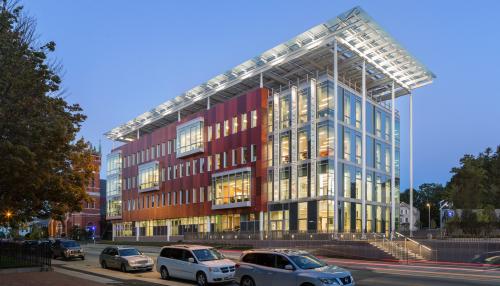 A 4 story academic building with a large white solar canopy structure above