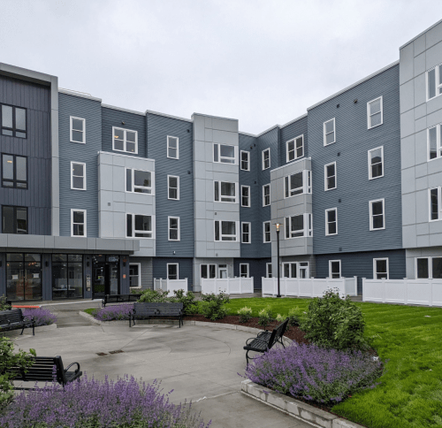 view of 4 story multifamily building facade and landscaping in front