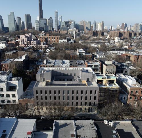A modern, four-story gray residential building with a flat roof and a central courtyard.