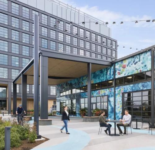 Exterior of the warehouse looking structure featuring a overhang matching the new construction and a colorfully painted mural facade