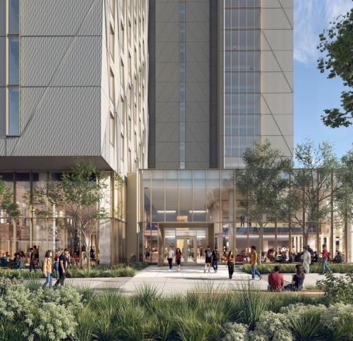 A modern multi-story building featuring a textured, geometric facade above a transparent, glass-enclosed ground floor with prominent structural columns.