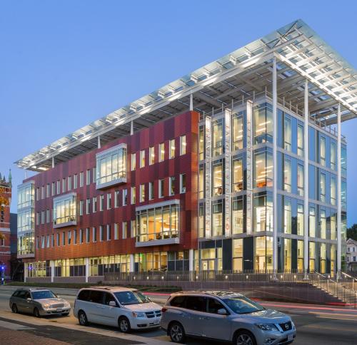 A 4 story academic building with a large white solar canopy structure above